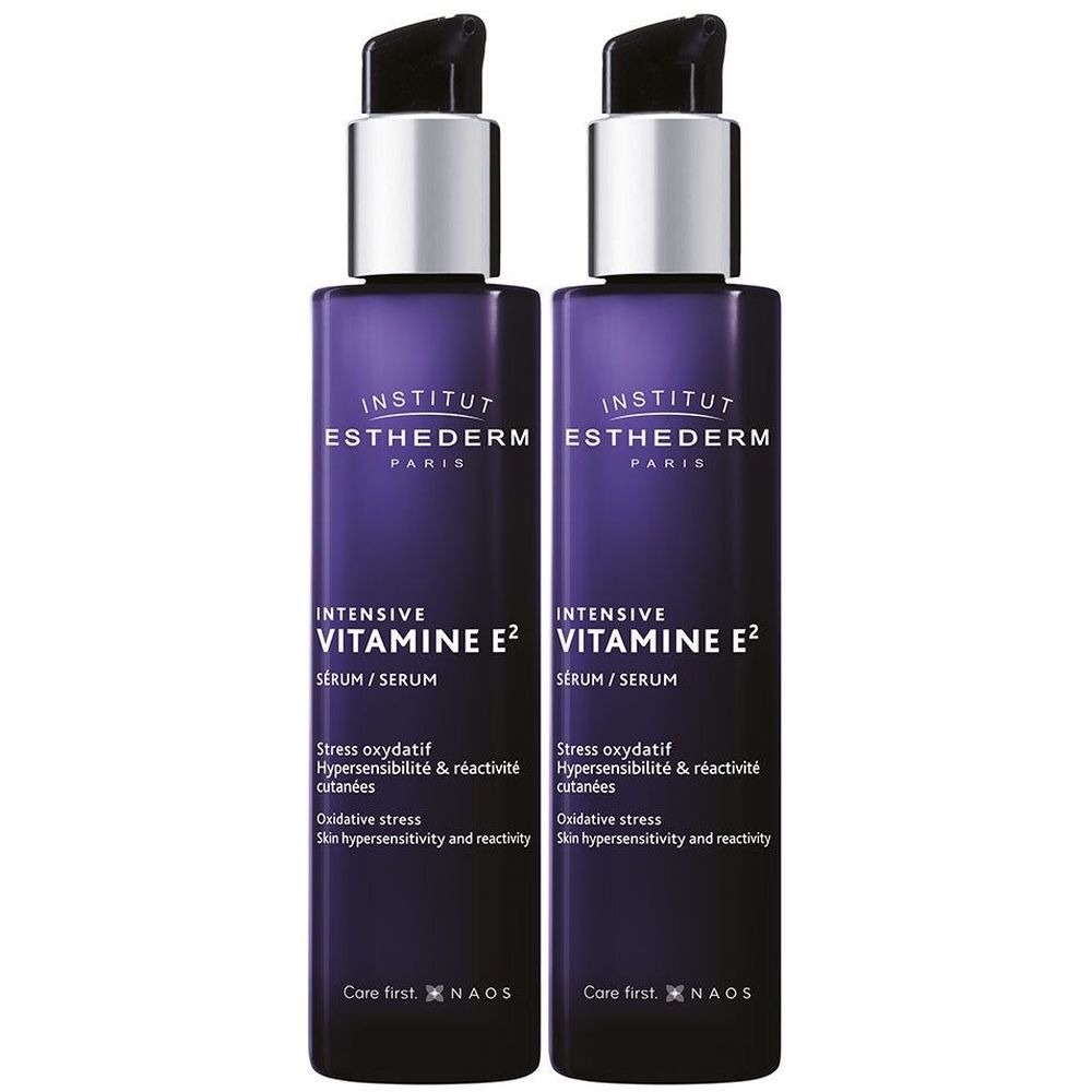 Twee flessen INSTITUT ESTHEDERM Intensiv-Vitamin E2 serum. Paarse flessen met zilveren pompkopjes. Tekst: Intensiv Vitamin E2, Serum.