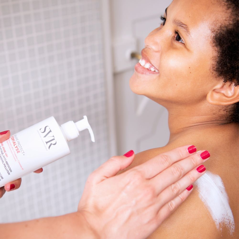Persoon brengt crème aan op schouder. Fles met SVR-logo en productnaam. Tekst: Baume Protect + Topialyse.