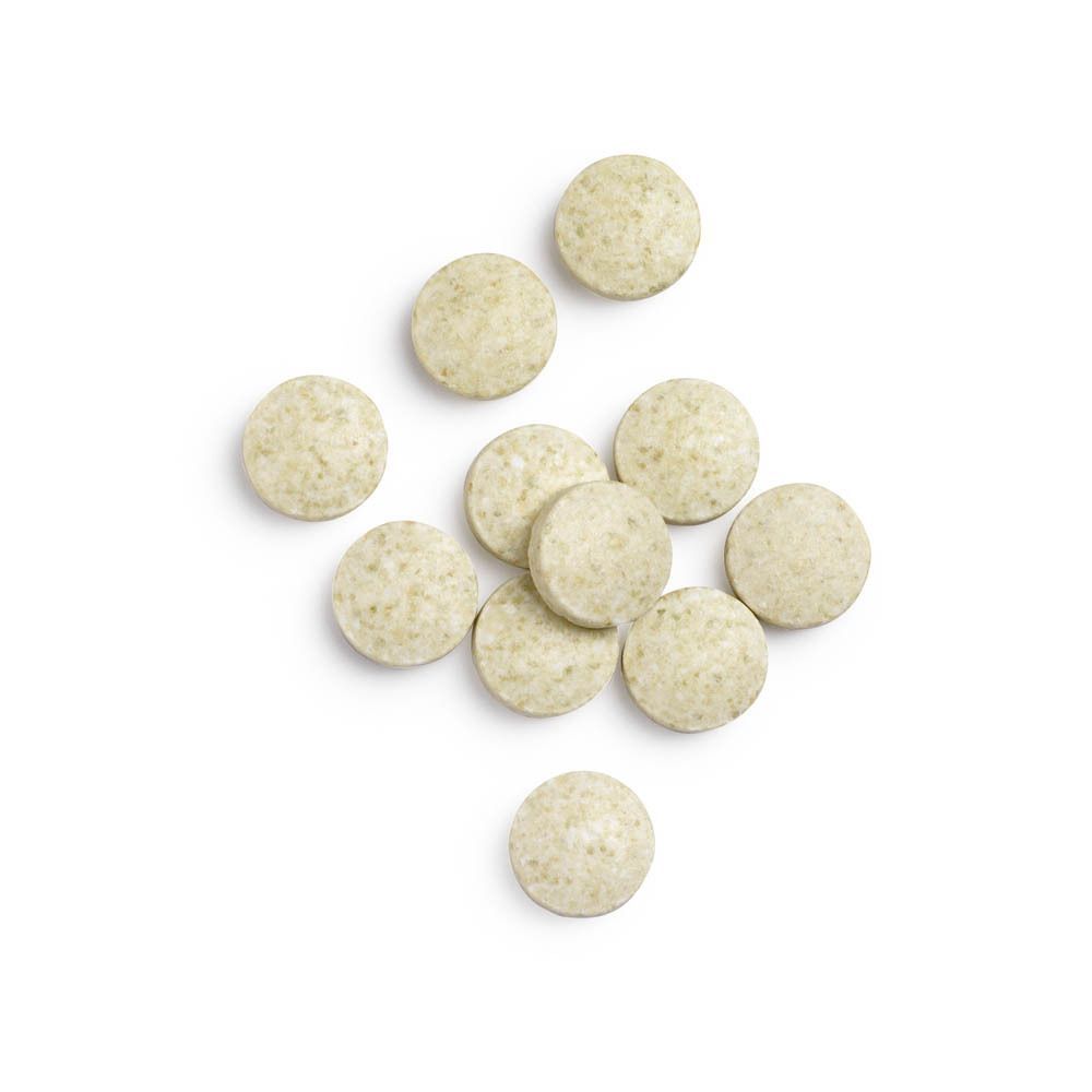 Plusieurs comprimés ronds de zinc de couleur vert clair sur fond blanc.