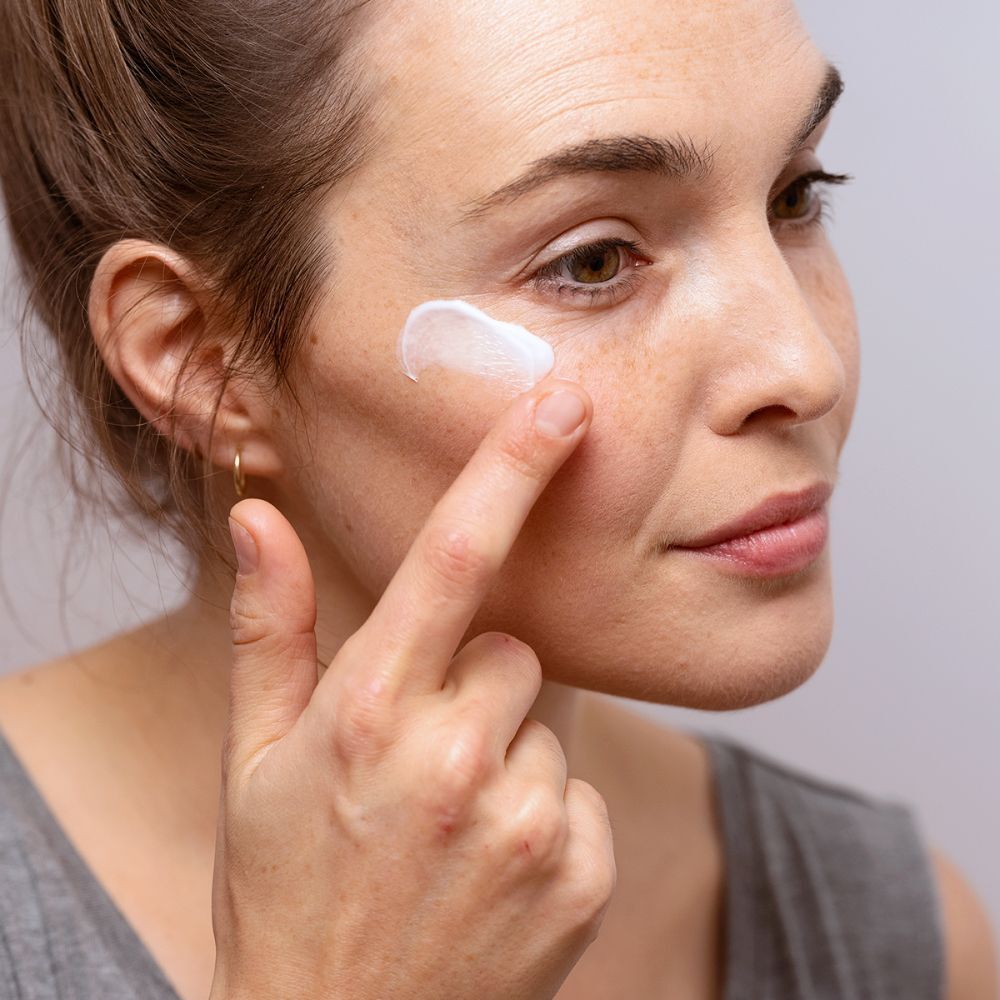 Vrouw brengt oogcrème aan. Merk SVR, productnaam CREME PALPEBRAL. Tekst: Anti-jeuk, geïrriteerde oogleden.