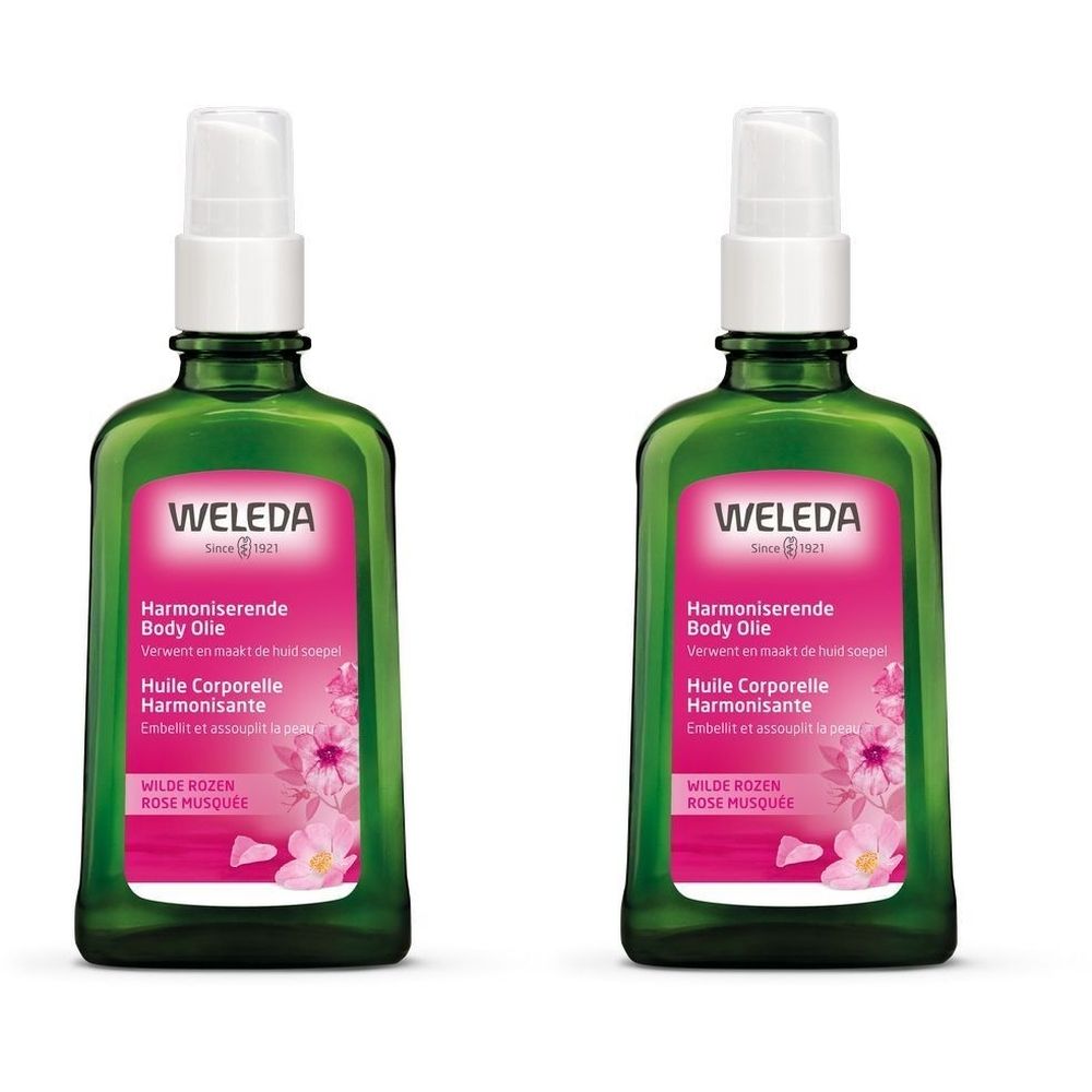 Twee groene flacons met verstuiver. Het etiket toont "WELEDA", "Harmoniserende Body Olie" en "Huile Corporelle Harmonisante".