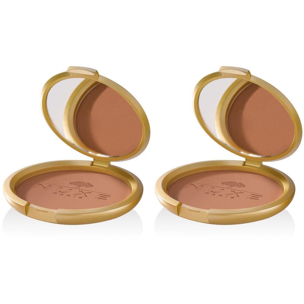 Deux poudriers dorés ouverts, révélant une poudre bronzée et un miroir. Logo NUXE visible sur le boîtier.