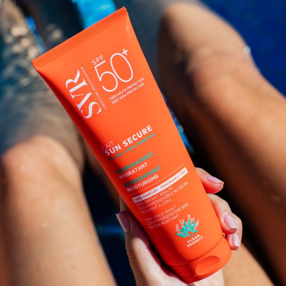 Oranje tube SVR Sun Secure Sonnenmilch SPF50+ vastgehouden door een persoon. Tekst: Lait Sun Secure, SPF 50+, hydratant, fini invisible.