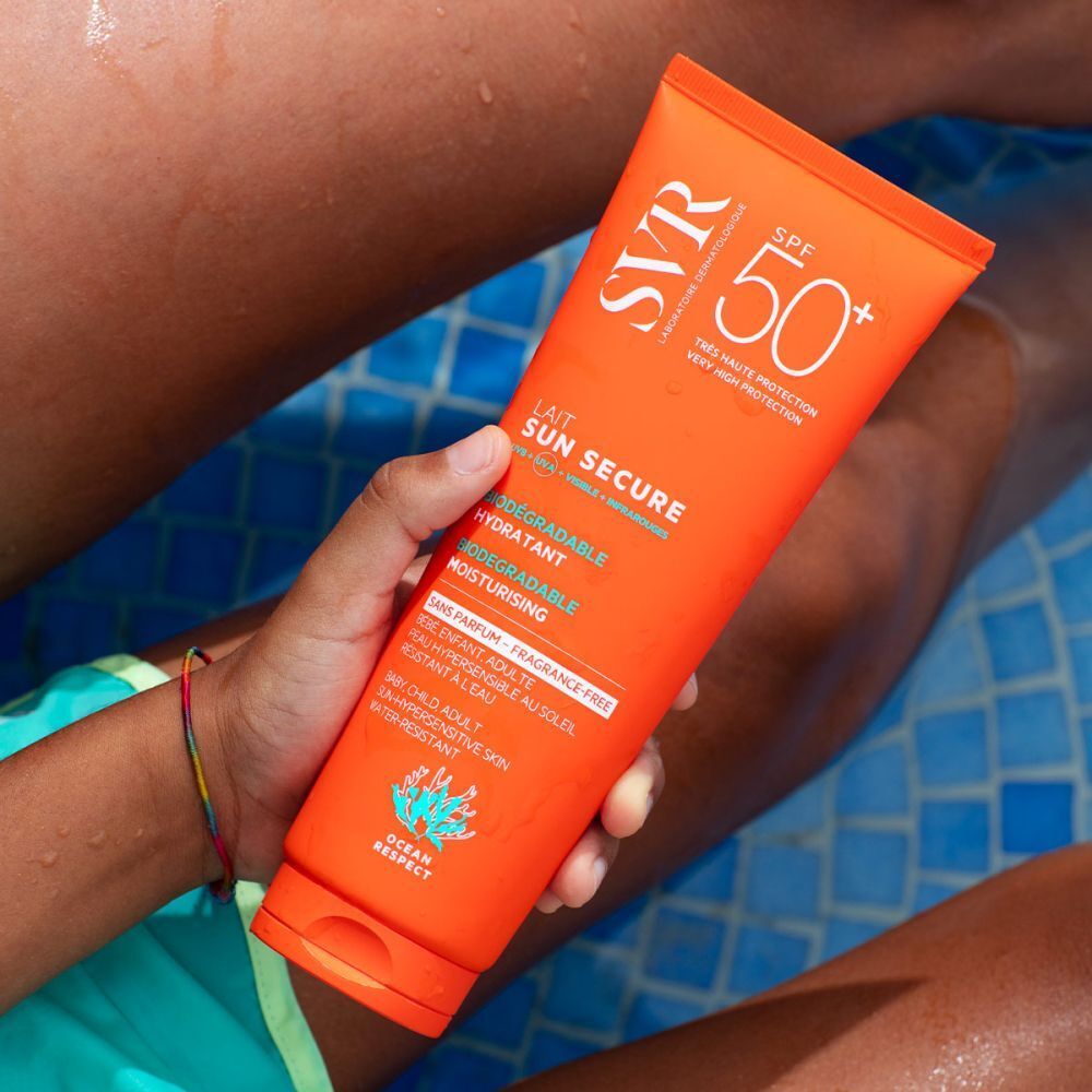 Oranje tube SVR Sun Secure Sonnenmilch SPF50+ vastgehouden door een persoon. Tekst: Lait Sun Secure, SPF 50+, hydratant, fini invisible.