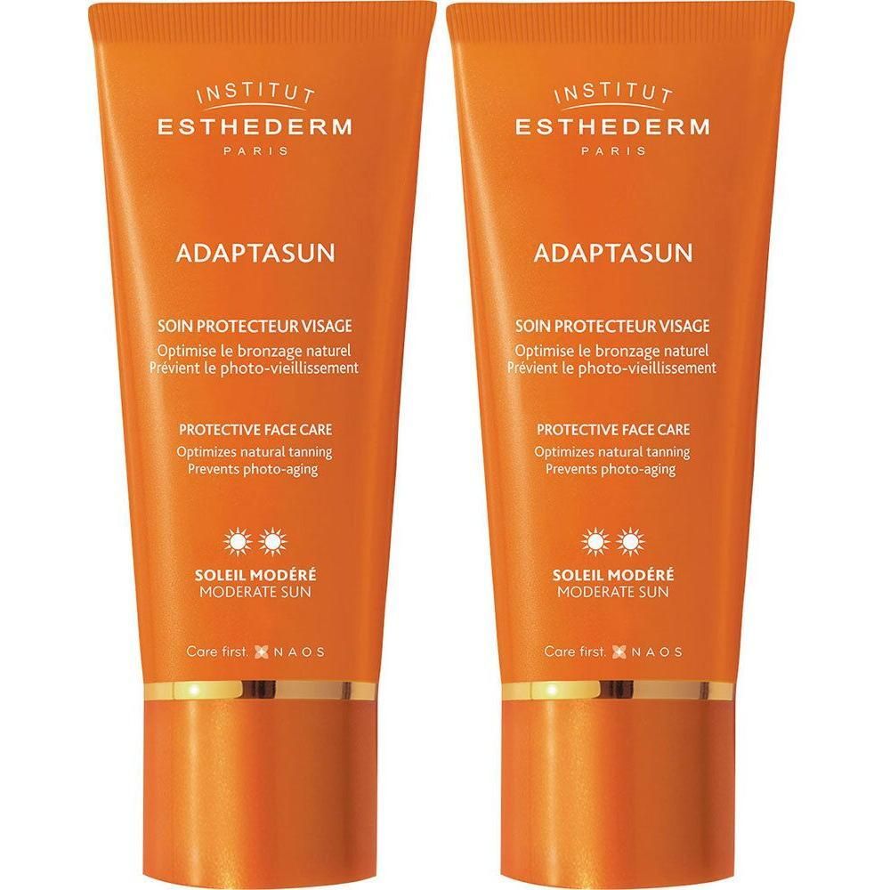 Twee oranje tubes Adaptasun, tekst en logo zichtbaar. Soleil Modéré, Protective Face Care.