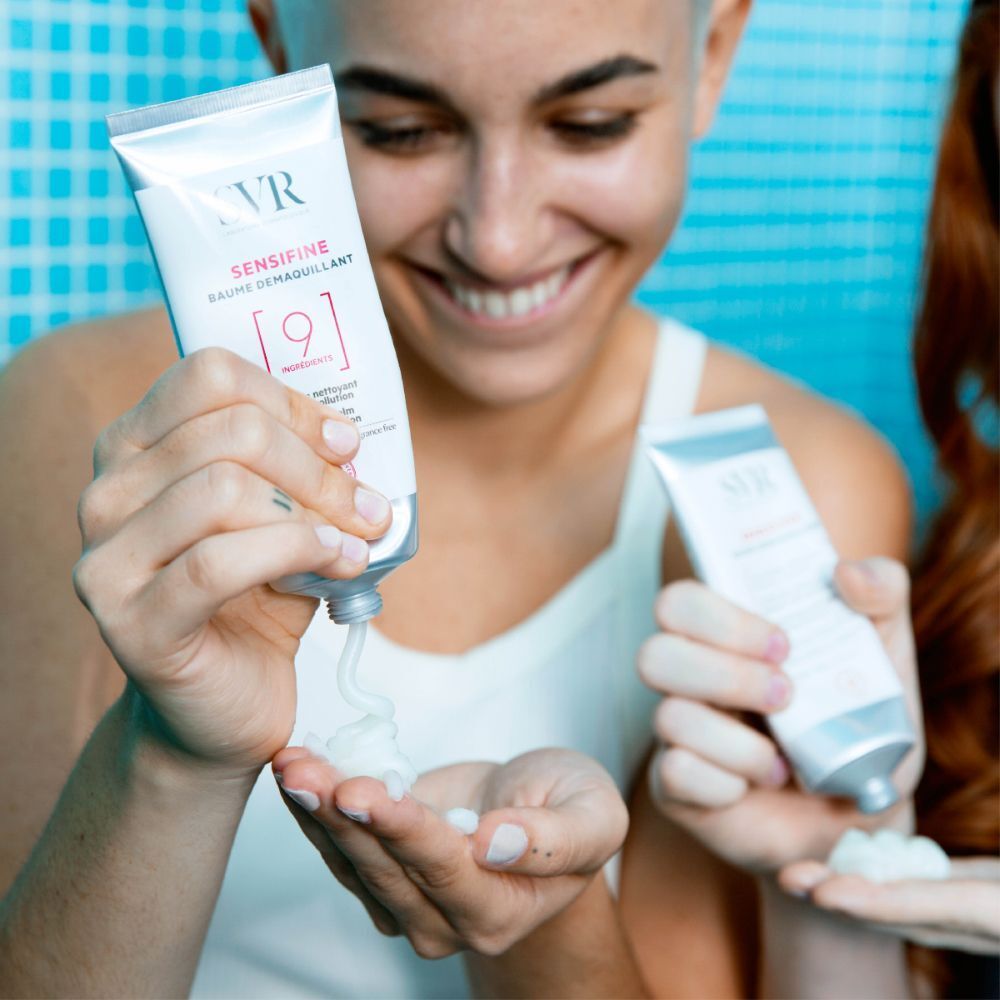 Des personnes tiennent des tubes de SVR Sensifine Baume Demaquillant. Le produit est pressé sur la paume. Nom et logo du produit visibles.