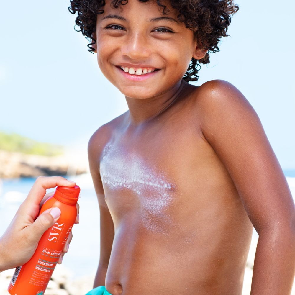 Kind krijgt een oranje spray op de borst. Zichtbaar: spray, huid.