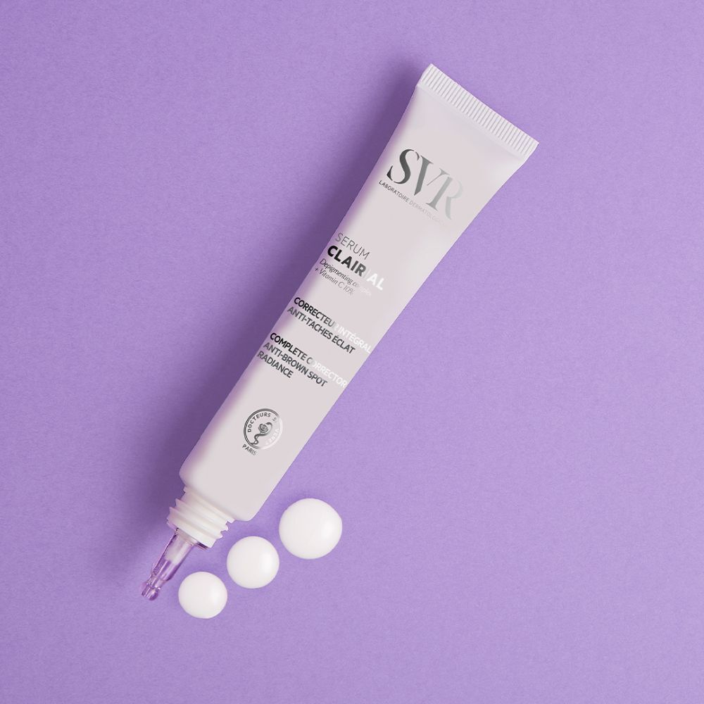 SVR Clairial Serum tube en druppels op paarse achtergrond. Tekst: Clairial Serum, Corrector intégral anti-taches éclat.