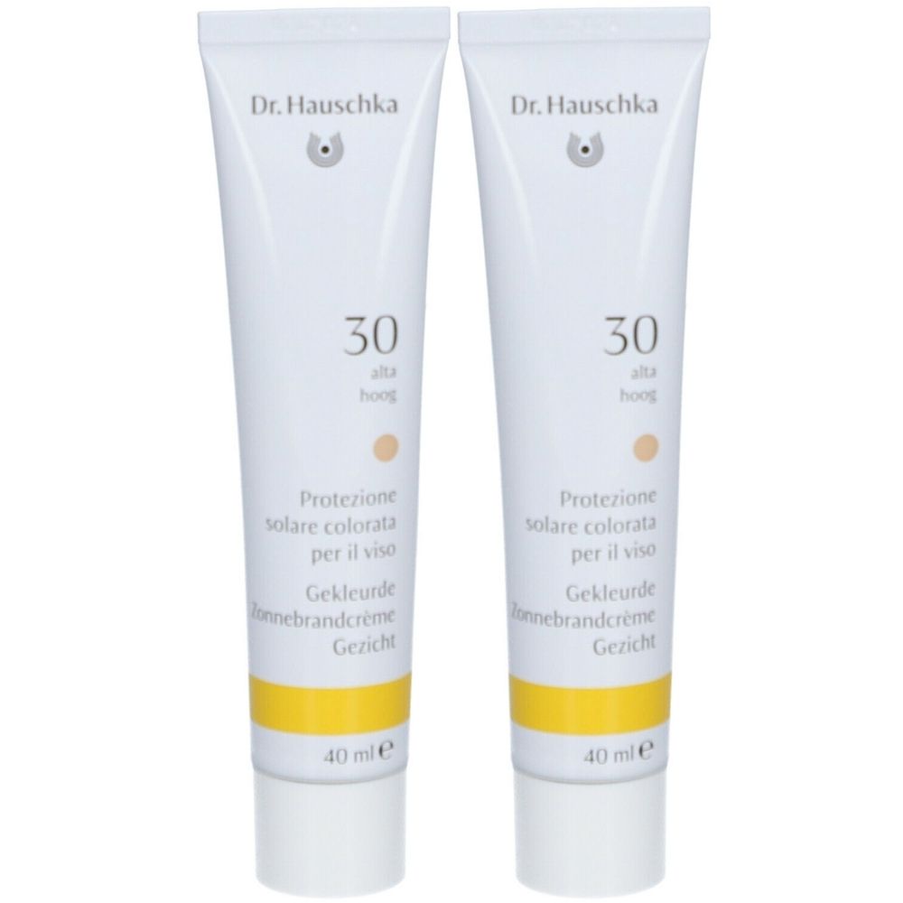 Twee tubes Dr. Hauschka getinte zonnecrème SPF 30. Witte tubes met gele band en meertalige productaanduidingen.