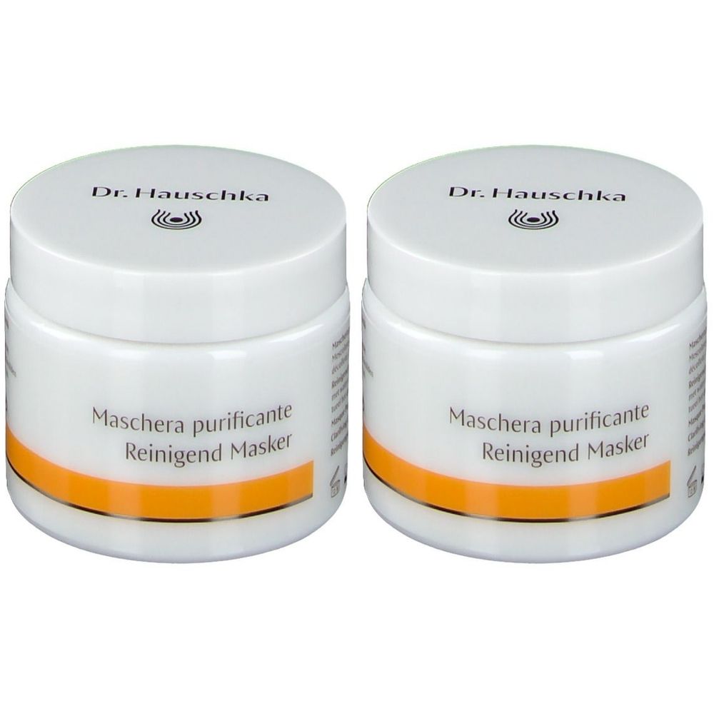 Twee witte potten met deksels. Opschrift: Dr. Hauschka, Maschera purificante, Reinigend Masker. Oranje streep.