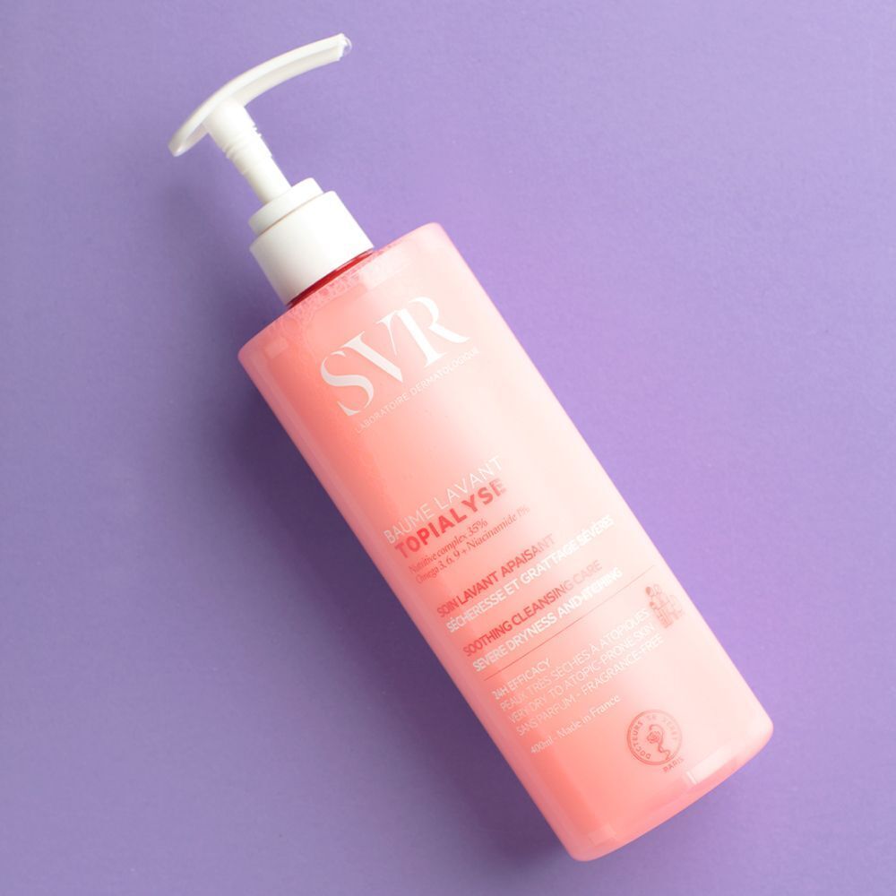 Roze fles met witte pomp. Opschrift SVR, TOPIALYSE, Baume Lavant. Fles ligt op een paarse ondergrond.