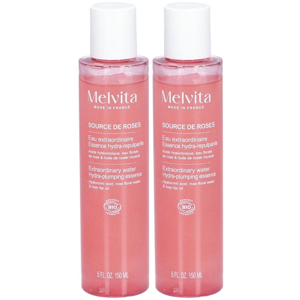Deux flacons de Melvita Source de Roses. Liquide rose, bouchon blanc. Texte: Eau extraordinaire, Essence hydra-repulpante.