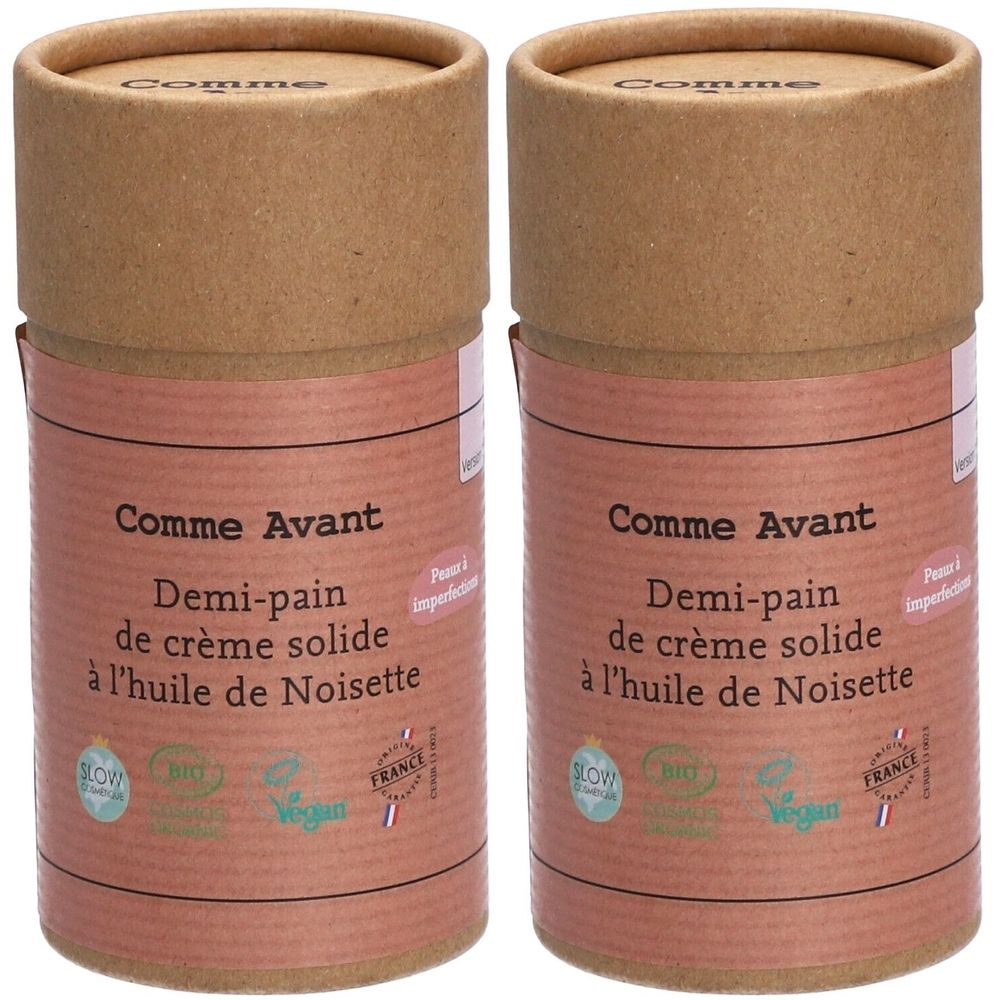 Deux contenants cylindriques. Inscription: Comme Avant, Demi-pain de crème solide à l'huile de Noisette. Avec labels bio et vegan.