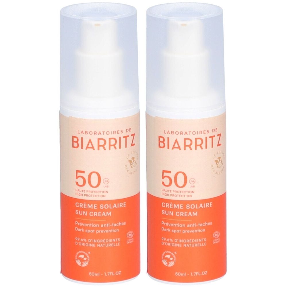 Twee flessen zonnecrème SPF 50. Opschrift: LABORATOIRES DE BIARRITZ, Crème Solaire Sun Cream. Oranje-wit design.