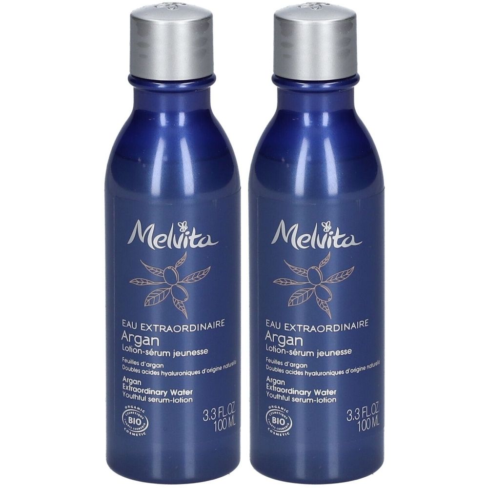 Twee blauwe flessen met zilveren doppen. Opschrift: Melvita, Eau Extraordinaire Argan, Lotion-sérum jeunesse. Bio-certificering.