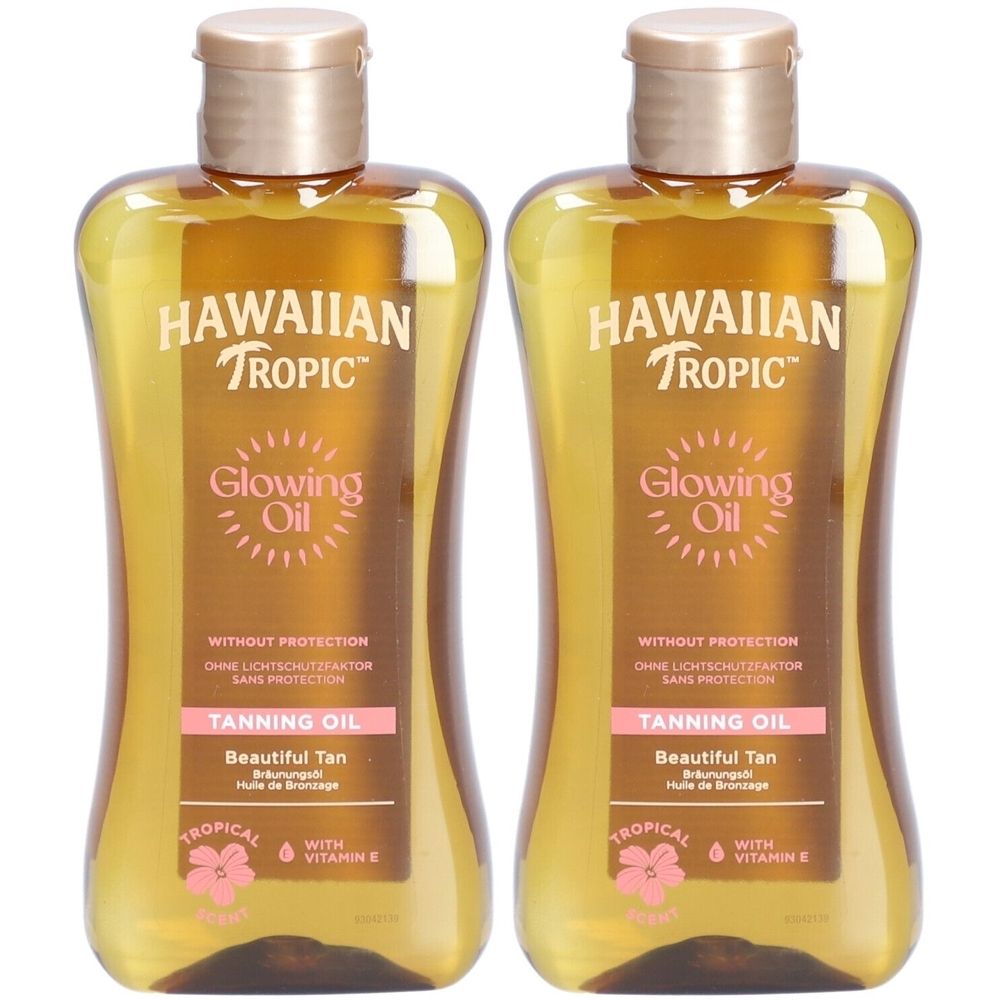 Twee flessen HAWAIIAN Tropic Glowing Oil. Goudkleurige vloeistof in transparante flessen met gouden doppen. Tekst: Tanning Oil.