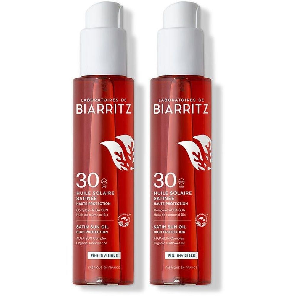 Twee flessen zonneolie met witte pomp. Opschrift: Laboratoires de Biarritz, 30, Huile Solaire Satinée, Fini Invisible.