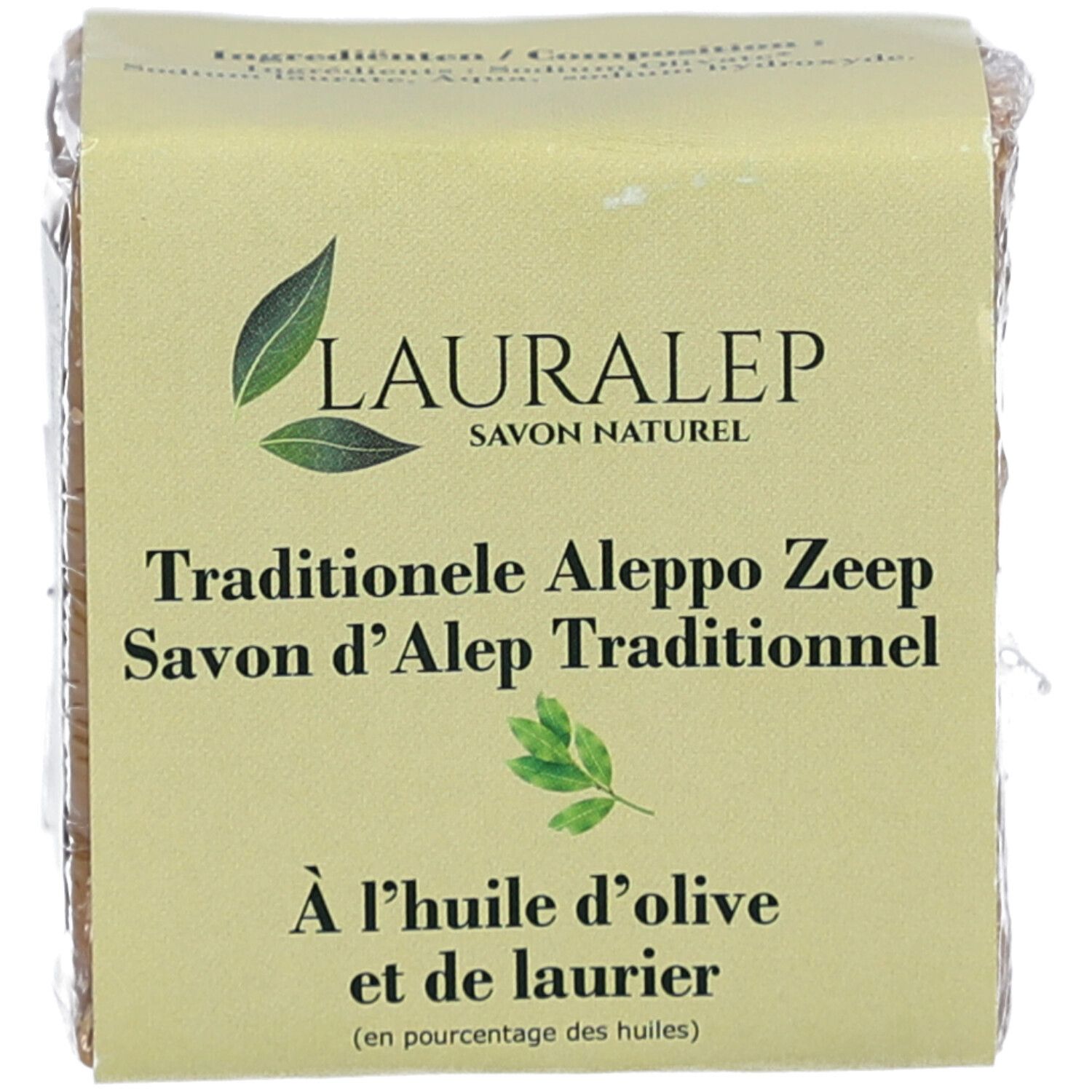 Vierkant stuk zeep verpakt in papier. Opschrift: LAURALEP, Savon Naturel. Tekst: Traditionelle Aleppo Zeep, Savon d'Alep Traditionnel, olijfolie.