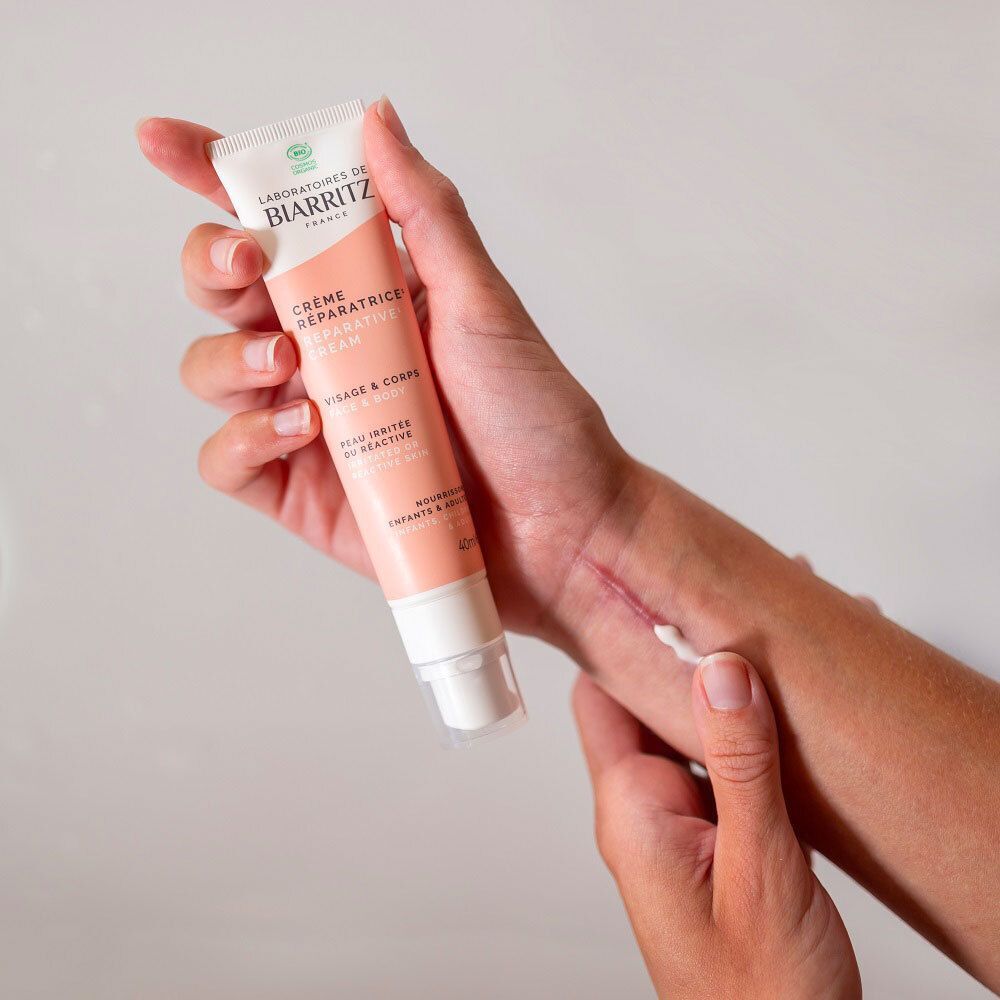 Close-up van een hand met een streep witte crème op de huid.