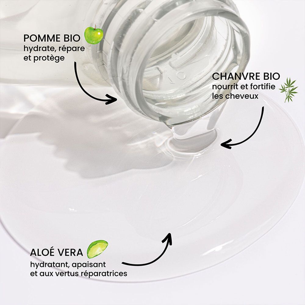 Gros plan de liquide s'écoulant d'une bouteille. Étiquettes : pomme, chanvre, aloe vera. Texte : hydrate, répare, protège.