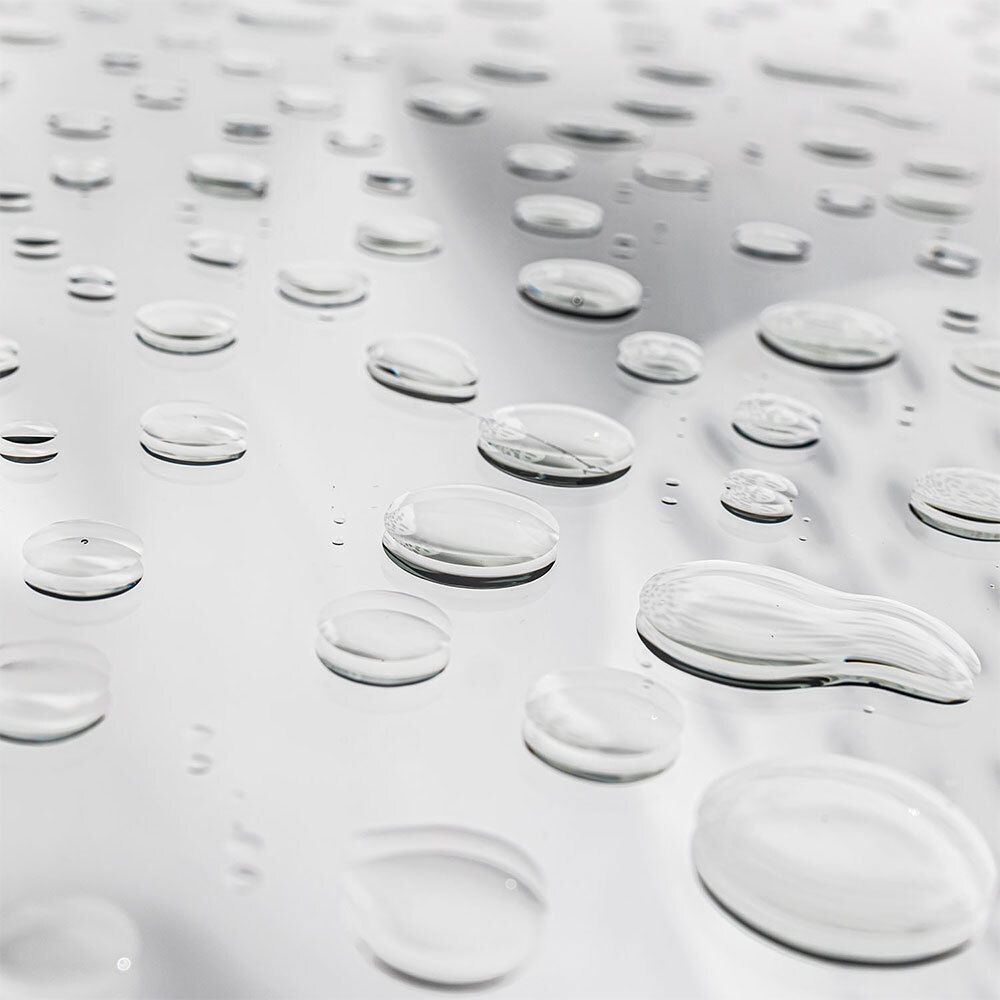Close-up van waterdruppels op een glanzend oppervlak. De druppels zijn helder en van verschillende groottes.