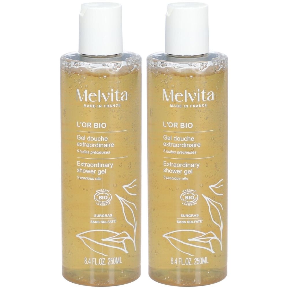 Twee flessen douchegel. Transparante gel met gouden kleur. Opschrift: Melvita, L'Or Bio, Extraordinary shower gel. Bio-certificering.