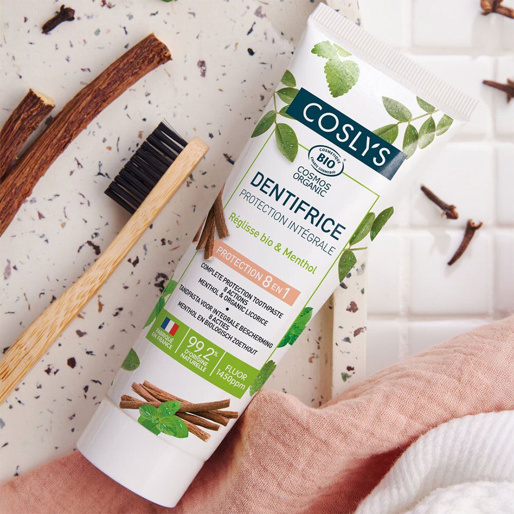 Coslys tandpastatube met houten tandenborstel en decoratieve elementen. Tekst "Dentifrice Protection Intégrale". Bio-certificering.