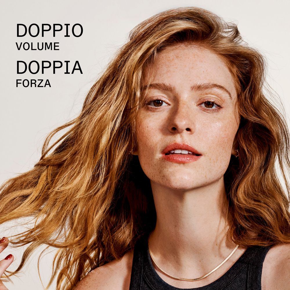 Femme aux cheveux roux et taches de rousseur, texte : DOPPIO VOLUME DOPPIA FORZA.