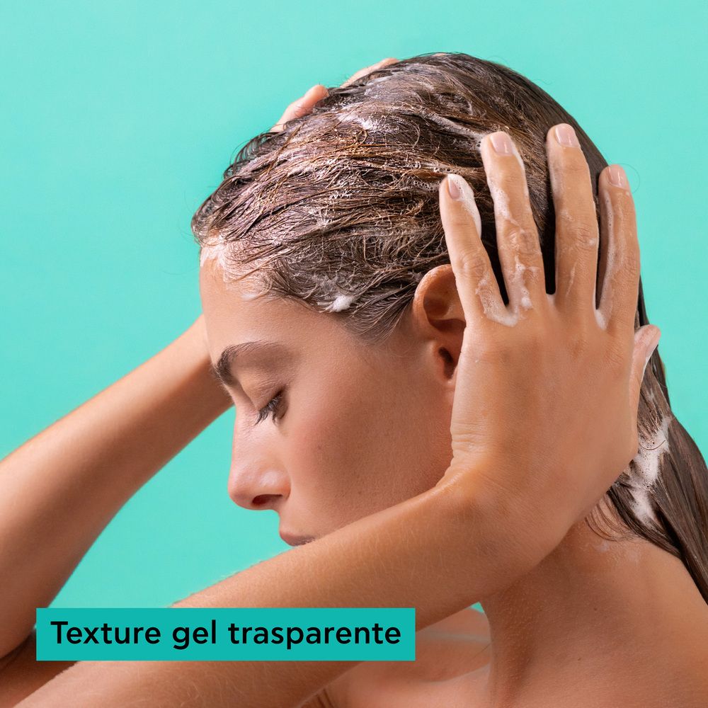 Femme appliquant un gel transparent sur ses cheveux mouillés, mousse sur le cuir chevelu et les mains.