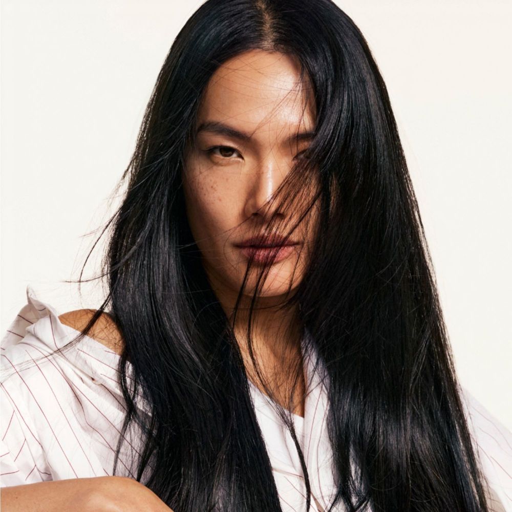 Gros plan d'une femme aux longs cheveux noirs. Elle regarde la caméra.