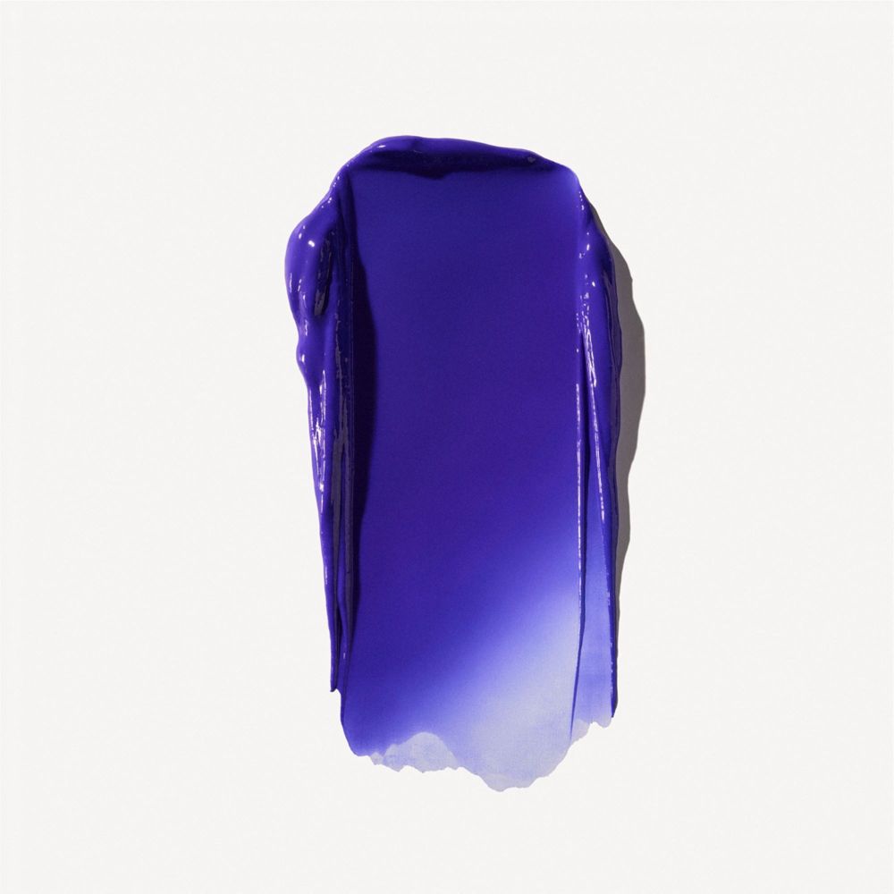 Étalement d'une crème violette. Sur fond clair. Texture visible.