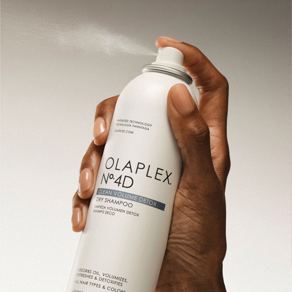 Witte spuitbus met Olaplex No. 4D Clean Volume Detox Dry Shampoo. Hand die spuit.