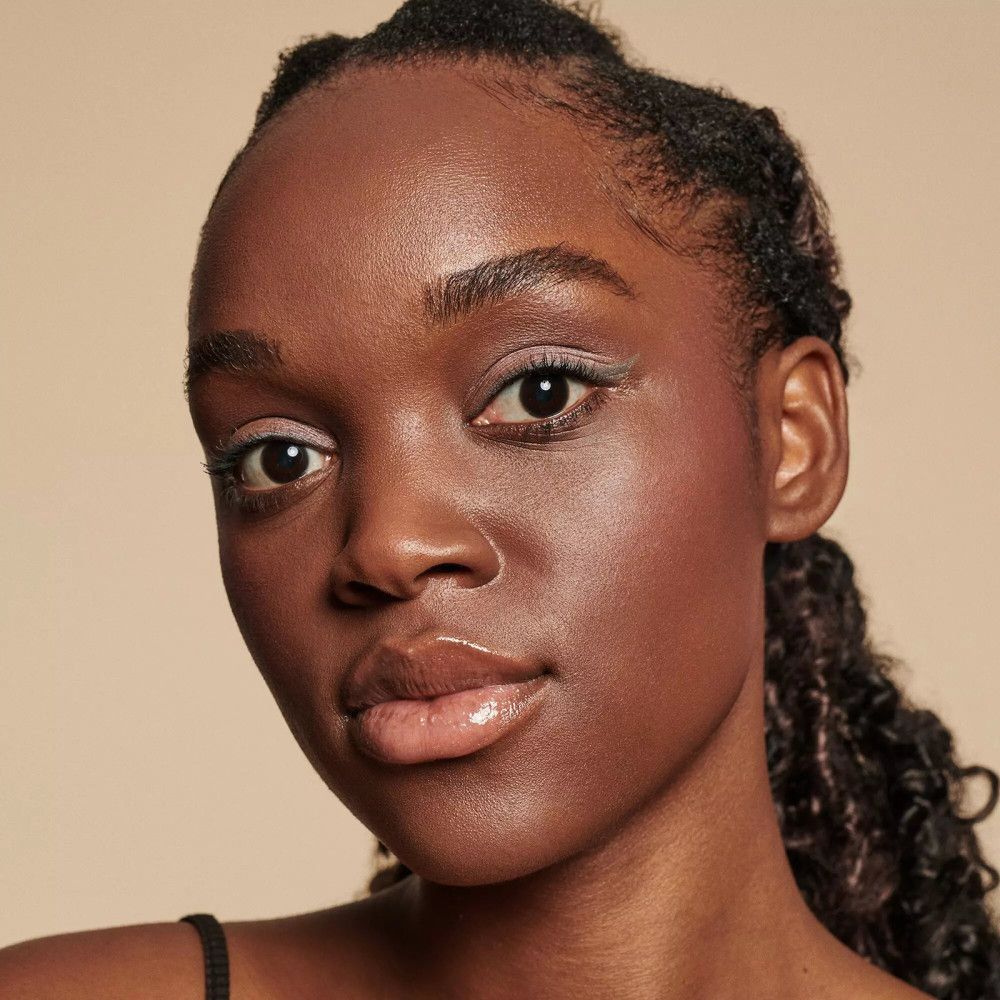 Portrait d'une femme avec fard à paupières rose et lèvres brillantes. Haut noir.