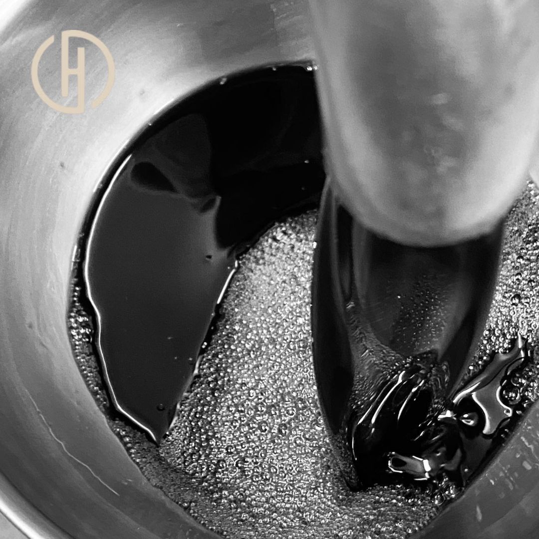 Gros plan sur de l'huile dans un bol. L'huile est agitée avec un outil. Logo "Hartlieb".