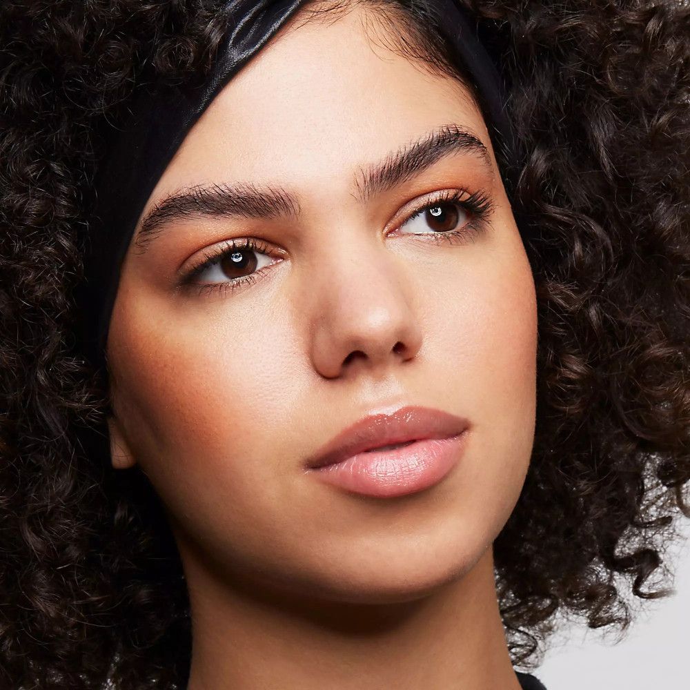 Portrait d'une femme maquillée. Accent sur les yeux et les lèvres. Sourcils mis en valeur, mascara visible.