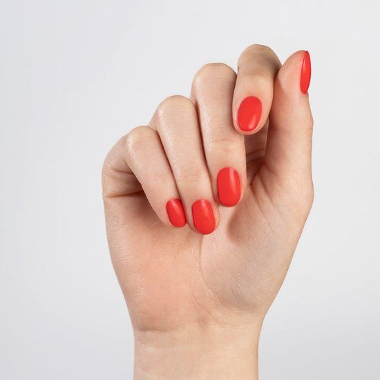 Main avec ongles vernis en rouge. Tous les ongles sont recouverts de vernis à ongles rouge.