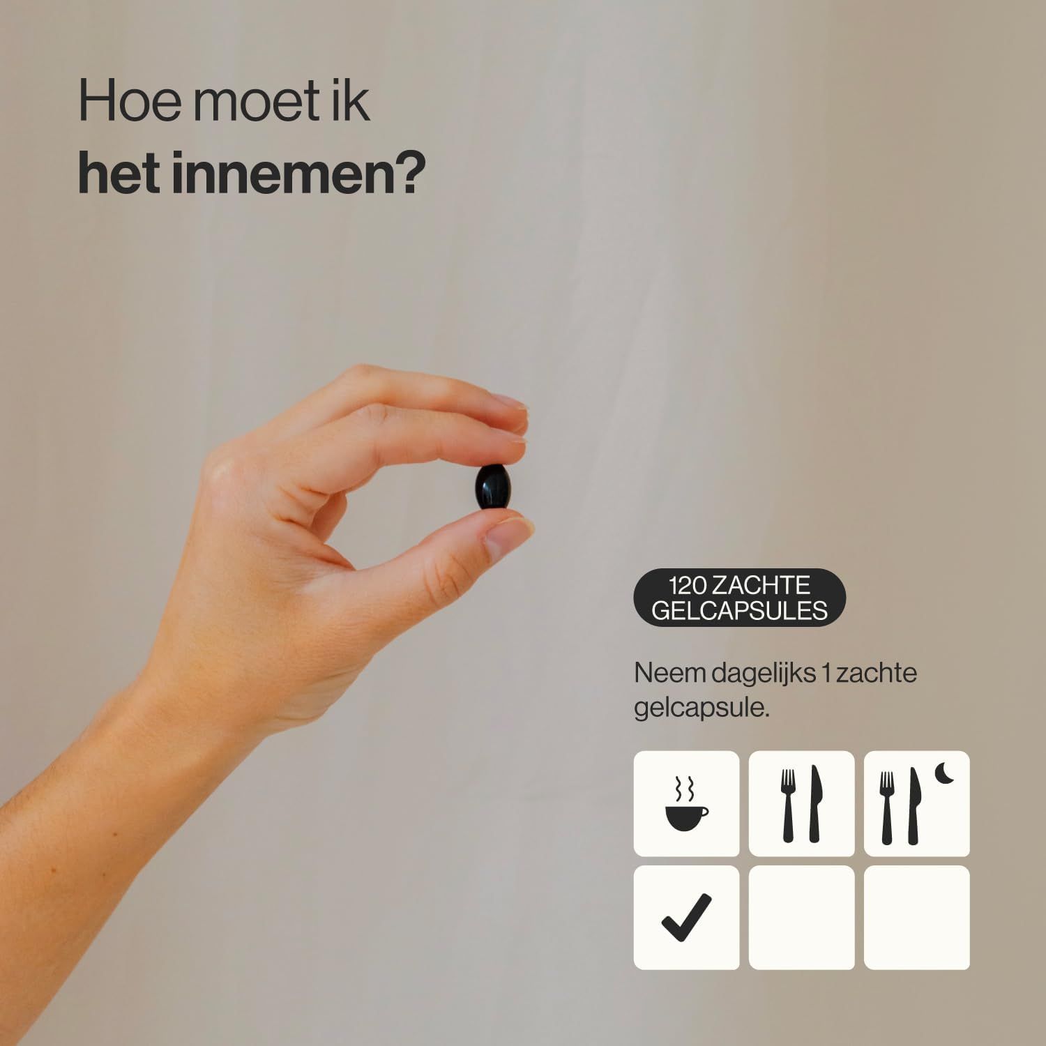 Een hand houdt een zwarte, ovale softgelcapsule vast tussen duim en wijsvinger.