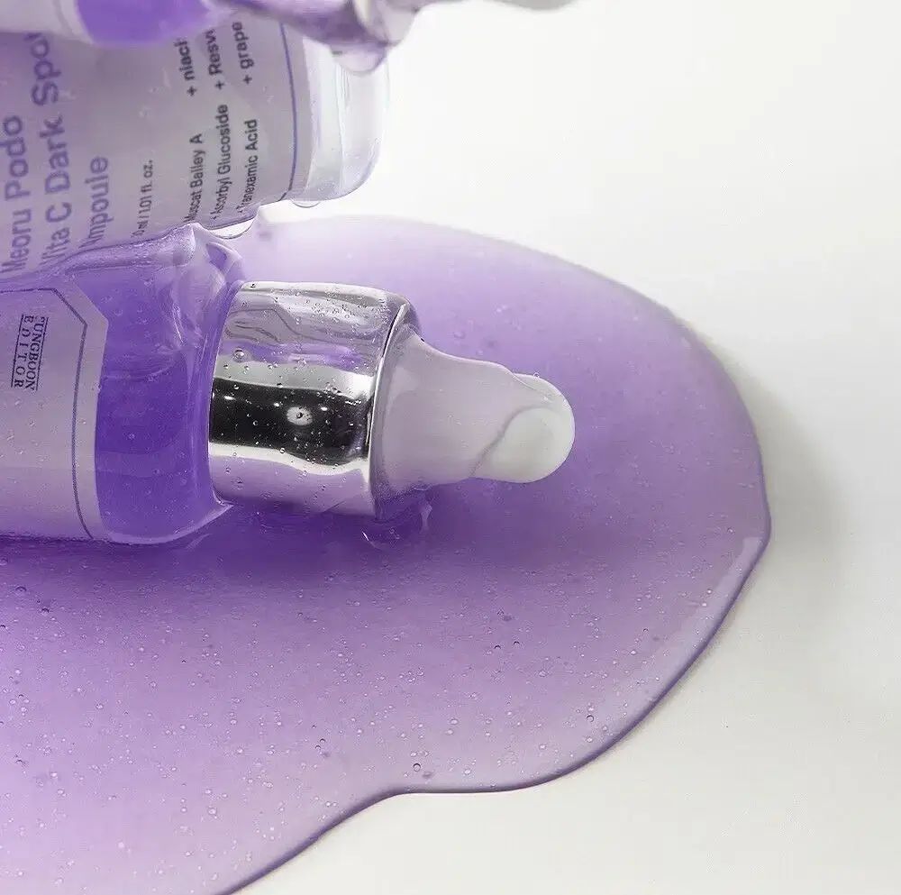 Paarse vloeistof op witte achtergrond. Flessen met pipetten. Productnamen zichtbaar op etiketten.