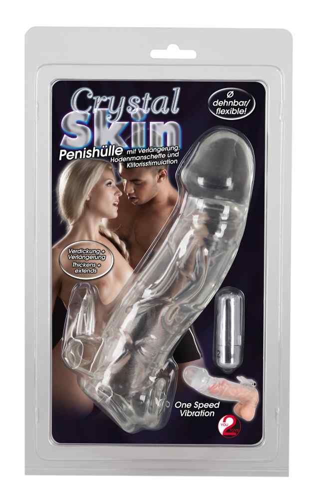Manchon pénien transparent dans un emballage. Inscription: Crystal Skin. Avec extension, stimulation des testicules et du clitoris. Flexible.