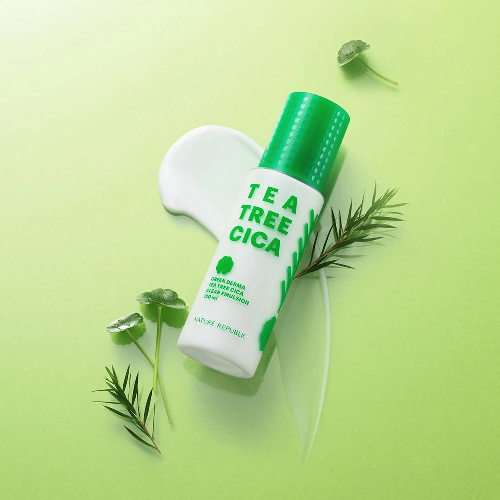 Flacon blanc et vert. Inscription: TEA TREE CICA. À côté, une goutte de crème et des feuilles vertes. Produit sur fond vert.