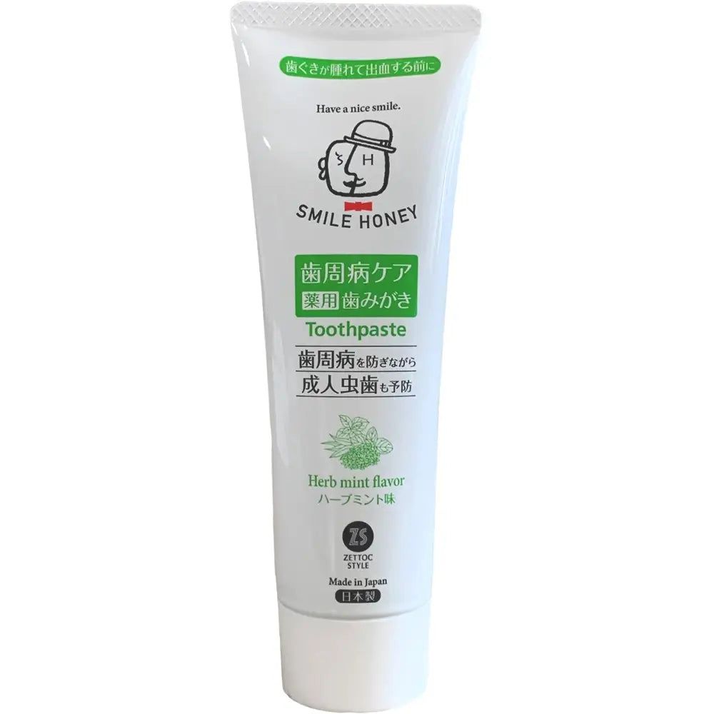 Witte tandpastatube met groene en zwarte tekst. Opschrift: SMILE HONEY, Toothpaste, Herb mint flavor.