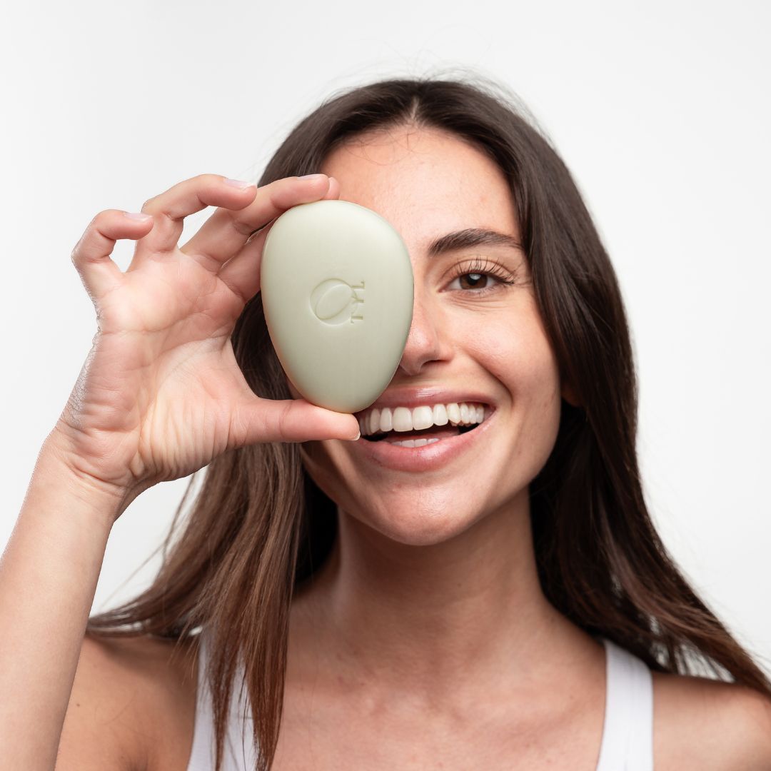 Ovale, lichte zeep voor een oog. Vrouw lacht. Zeep met logo.