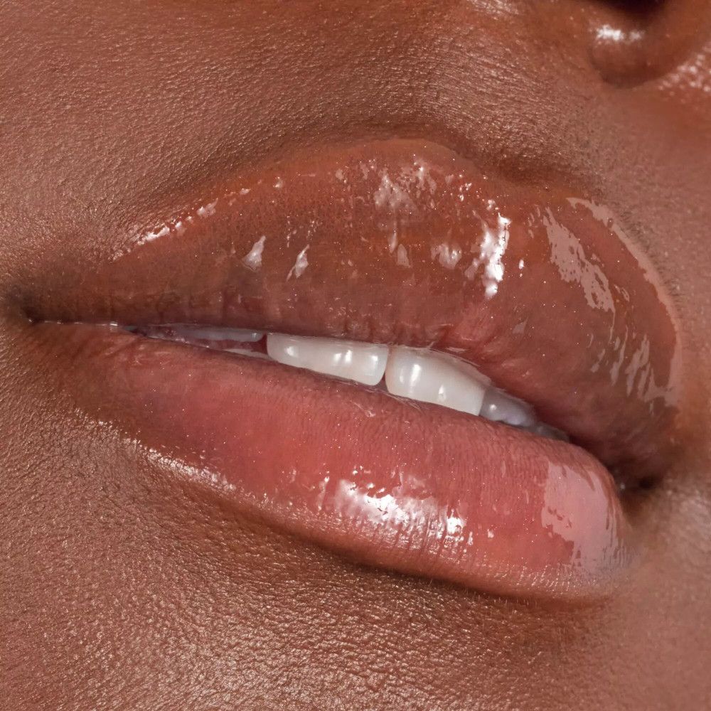 Close-up van lippen met glanzende lipgloss. De lippen zijn bruin en glanzend.