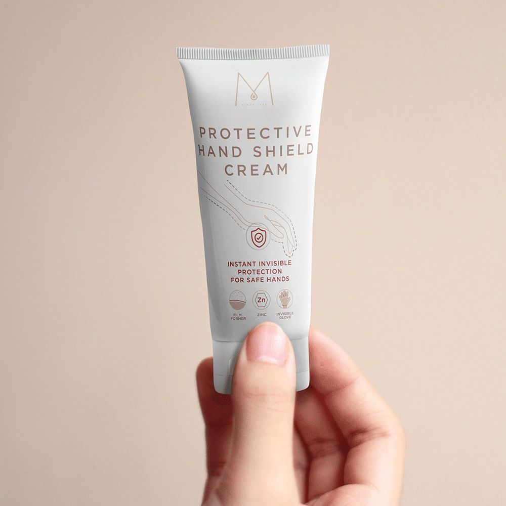Tube blanc MYLÈNE Protective Hand Shield Cream. Texte: Instant Invisible Protection for Safe Hands. Main tenant le tube.