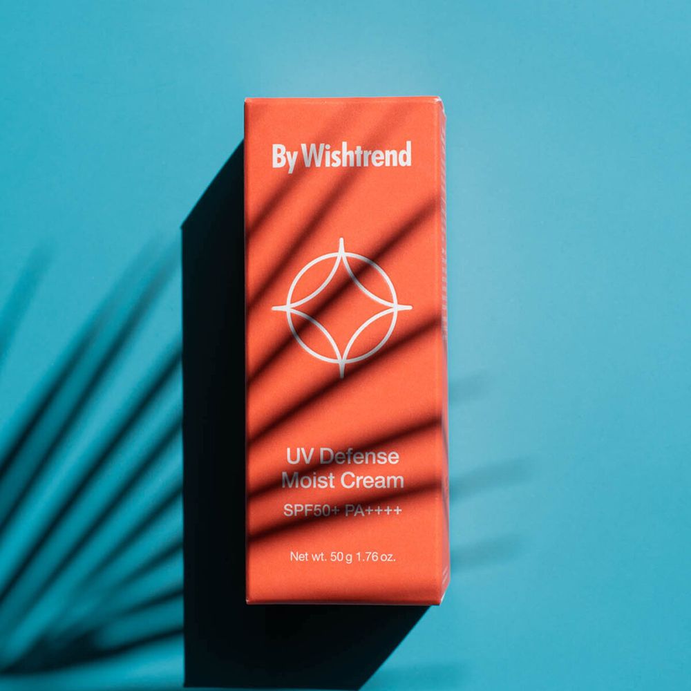 Oranje doos met bladerenschaduwen. Tekst: By Wishtrend, UV Defense Moist Cream SPF 50+ PA++++. Op blauwe achtergrond.