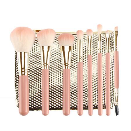 Ensemble de huit pinceaux de maquillage roses avec des accents dorés et une pochette dorée.