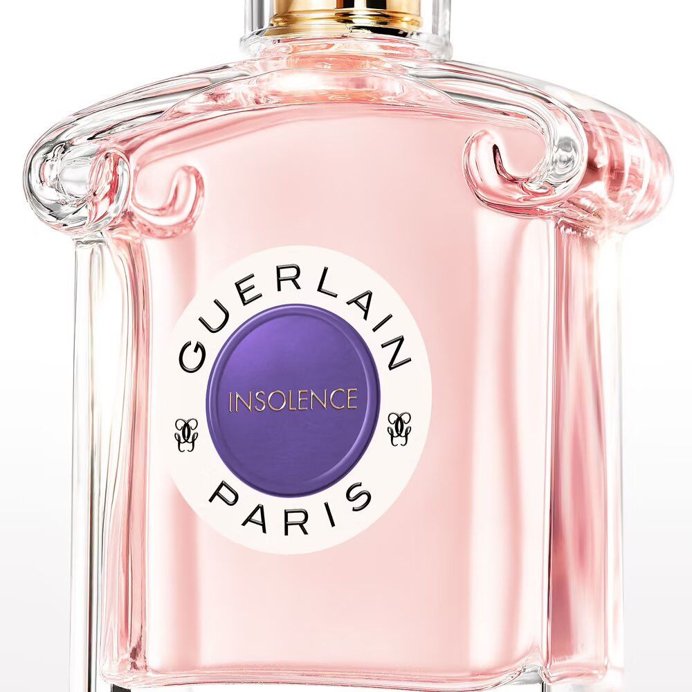 Flacon en verre rose. Étiquette « GUERLAIN INSOLENCE PARIS ». Forme ronde, bouchon doré.