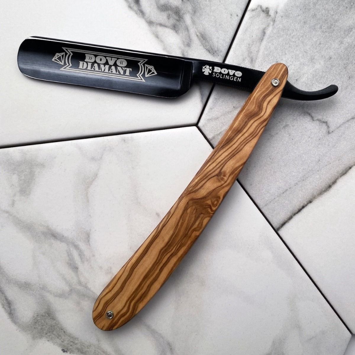 Scheermes met houten handvat. Lemmet met gravure "DOVO DIAMANT". Zwart lemmet, houten handvat. Op tegeloppervlak.