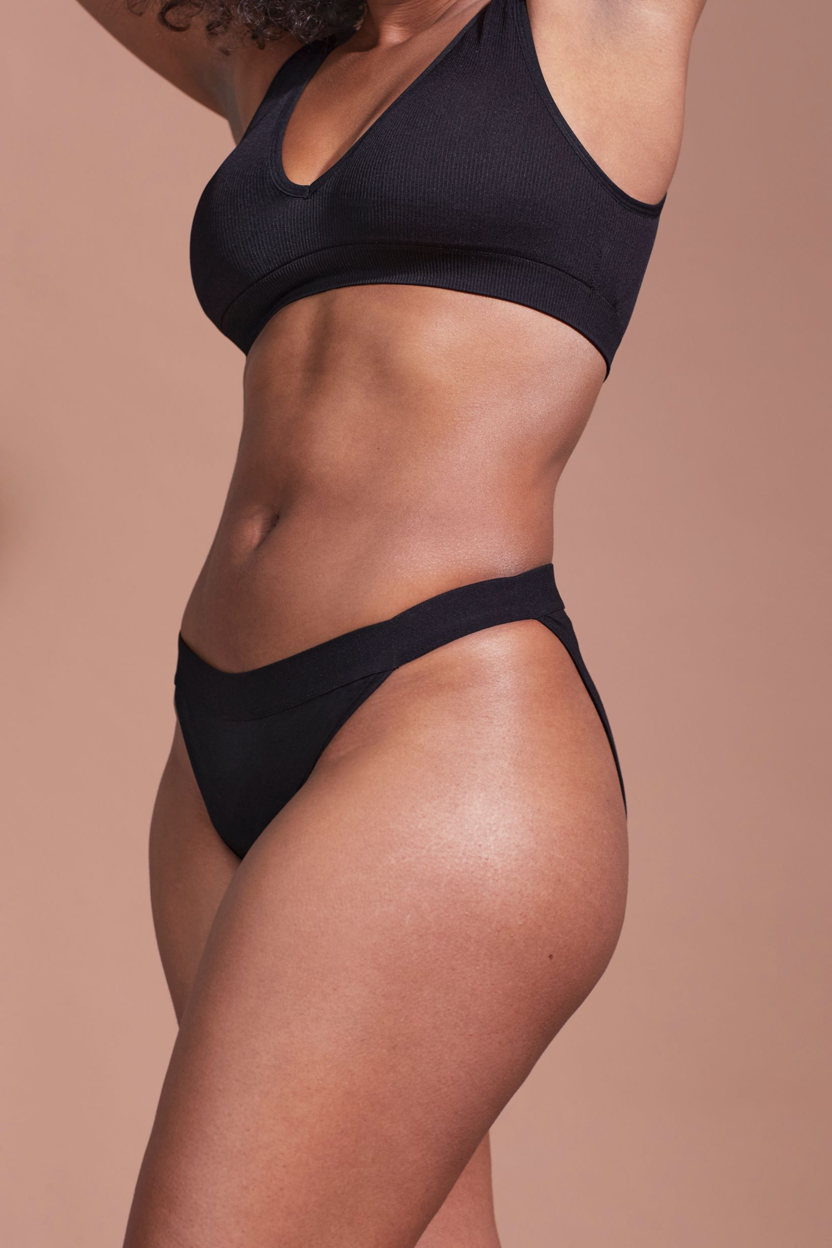 Culotte et soutien-gorge noirs. Femme de profil. Tissu côtelé.