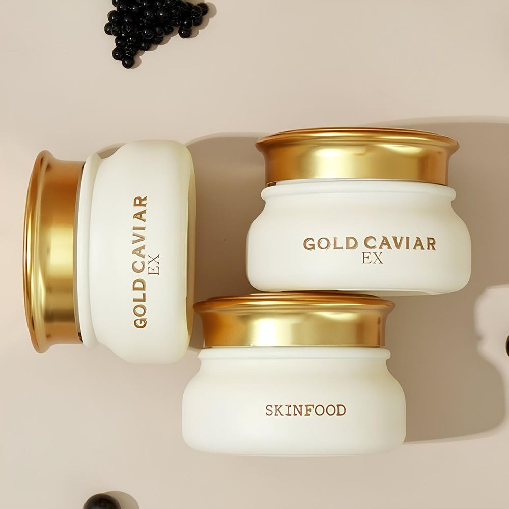 Trois pots de crème avec couvercles dorés. Les pots portent les inscriptions "GOLD CAVIAR EX" et "SKINFOOD".